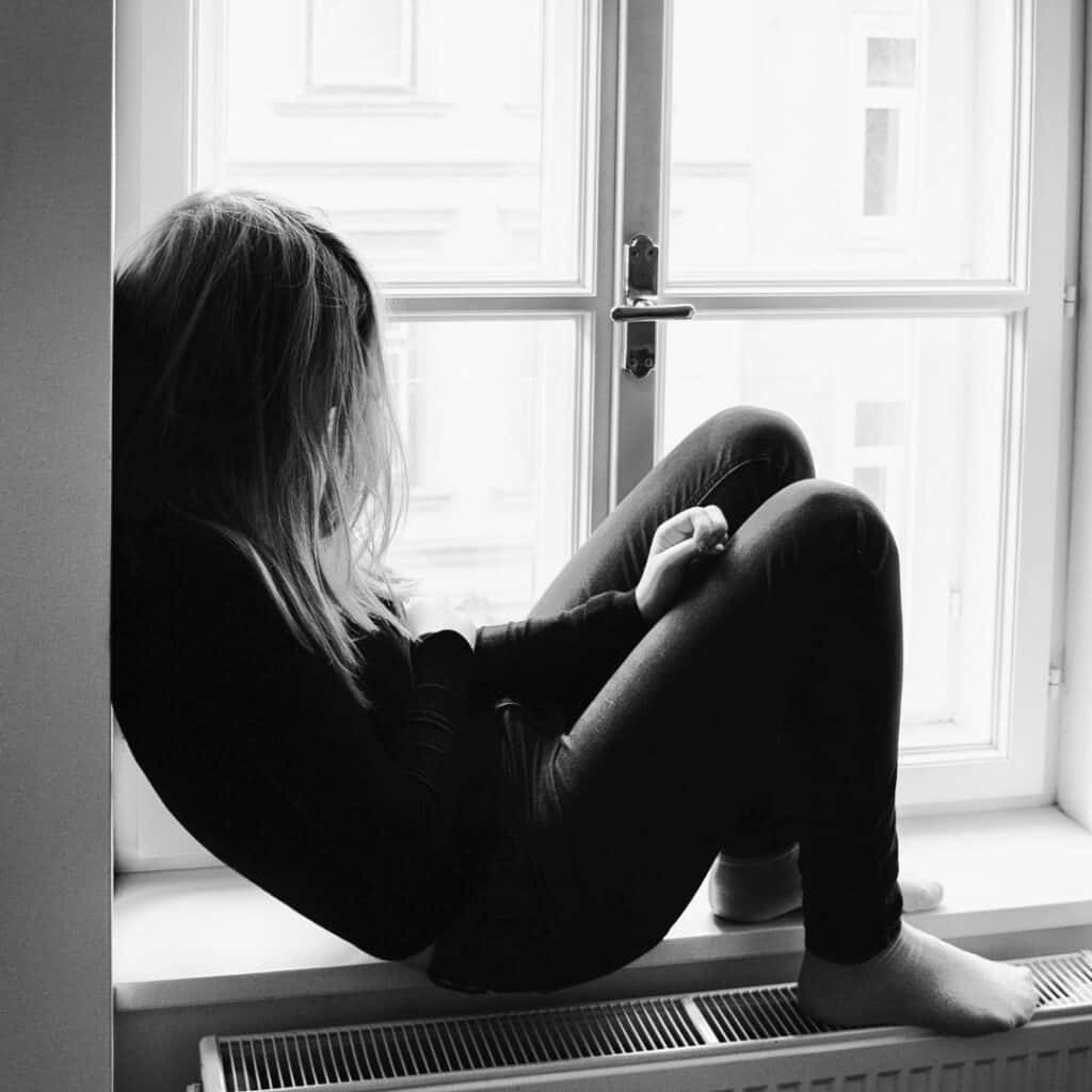Vrouw somber zittend in raamgat